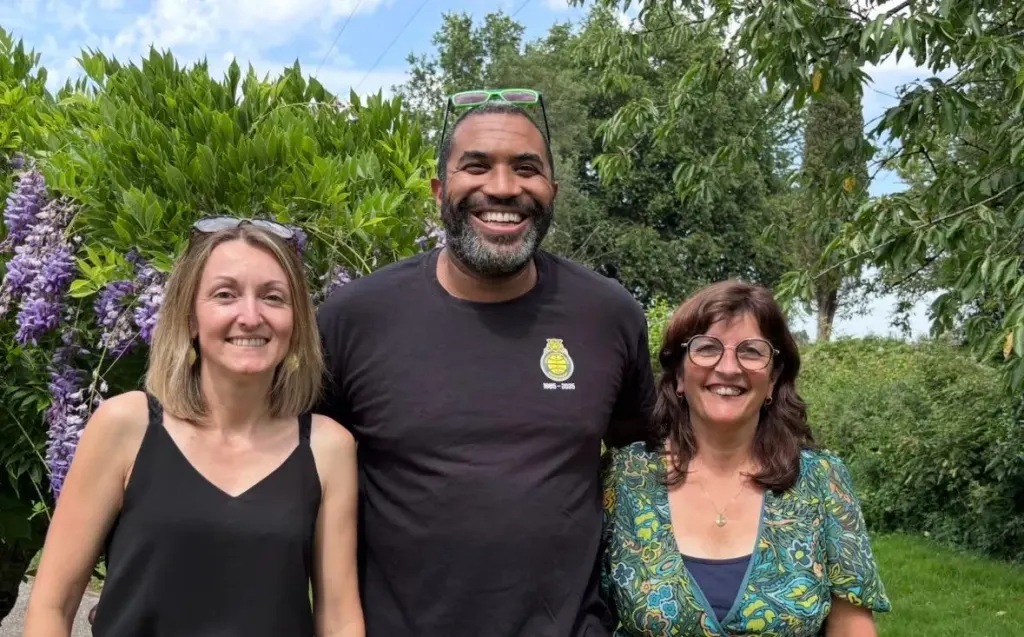 Les trois co-président·es de l’AS Brains Basket, souriant côte à côte devant une haie fleurie.